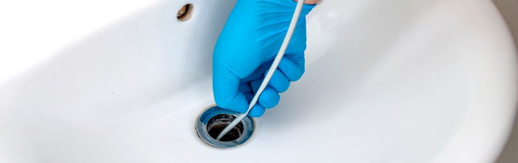 A plumber using a drain snake to clear a clogged drain in a Panama City, FL home.