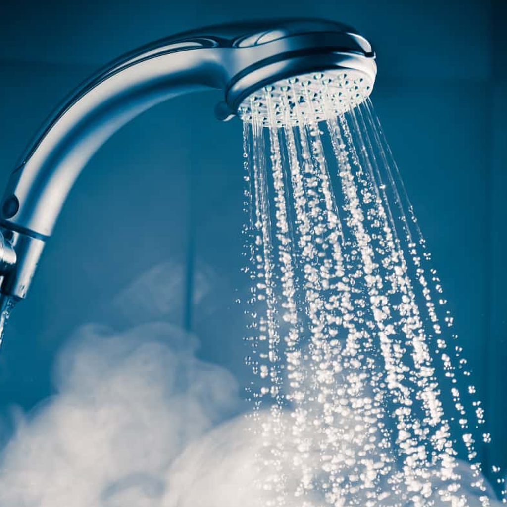 A shower head releasing steamy hot water, representing the endless hot water supply from a tankless water heater.